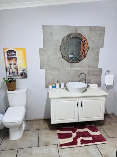 a bathroom with a sink and a toilet and a mirror at Casa De La Luna in Winterton