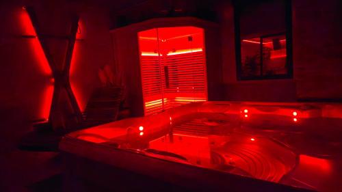 La salle de bains rouge est pourvue d'une baignoire avec des lumières rouges. dans l'établissement Espace évasions Loft Kis LOVE ROOM, à Toulouse