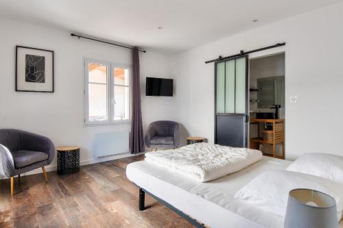 ein weißes Schlafzimmer mit einem Bett und zwei Stühlen in der Unterkunft 240m des plages - Maison avec jardin pour 12 in La Guérinière