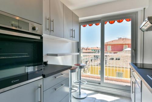 une cuisine avec des placards blancs et une grande fenêtre dans l'établissement Happyfew Fodere, à Nice