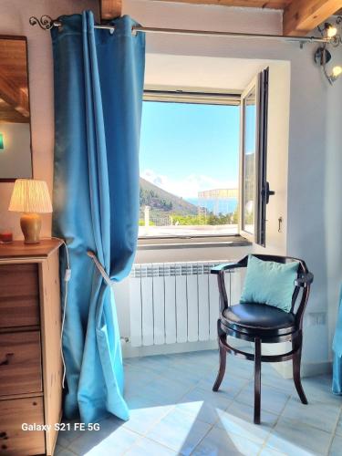 a chair in front of a window with a blue curtain at Casetta a Nerano in Nerano