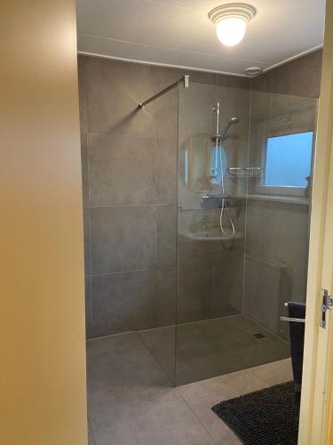 a bathroom with a shower with a glass door at Familiehuis Achter de Duijnhoeve Bakkum in Zuidbakkum