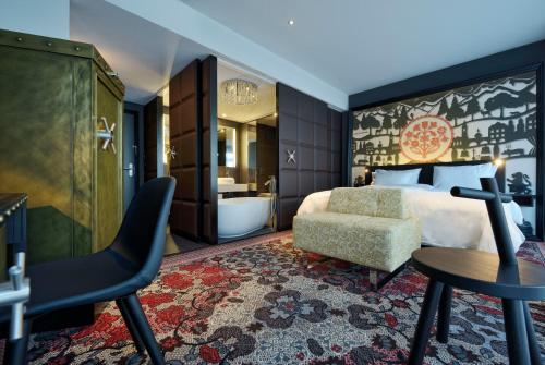 a bedroom with a bed and a chair and a tub at Kameha Grand Zurich, Autograph Collection in Glattbrugg