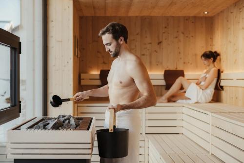 a man cooking food in a sauna with a woman at Pensione Camoscio in La Villa