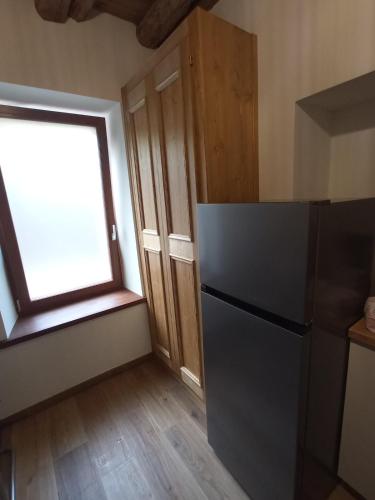 a kitchen with a black refrigerator and a window at Appartamento PT Sottocastello in Pieve di Cadore