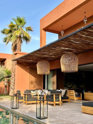 a patio with tables and chairs and a palm tree at Villa Madjha Ecolodge Marrakech in Marrakech