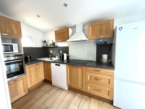 une cuisine avec des armoires en bois et un réfrigérateur blanc dans l'établissement Grand appartement, en bord de mer, 8 à 10 personnes, à Saint Pierre La Mer