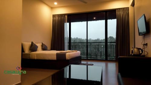 a bedroom with a bed and a balcony with a television at Casawyna Family Retreat Centre in Wayanad