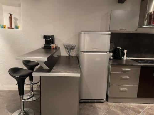 La cuisine est équipée d'un réfrigérateur et d'un comptoir avec tabourets. dans l'établissement Charmant duplex vue sur montagne, à Le Broc