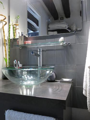 La salle de bains est pourvue d'un lavabo en verre sur un comptoir. dans l'établissement Studio Marais Charlot CityCosy, à Paris