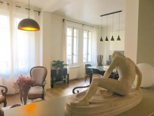 une statue d'un homme assis sur une table dans un salon dans l'établissement Luxe Marais Bretagne CityCosy, à Paris