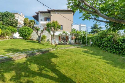 a house with a lawn in front of it at Τraditional fully detached villa on a luxurious hillock of Thessaloniki with its own garden also for family & wedding gatherings for 10 to 25 people only 15 minutes from airport in Thessaloniki