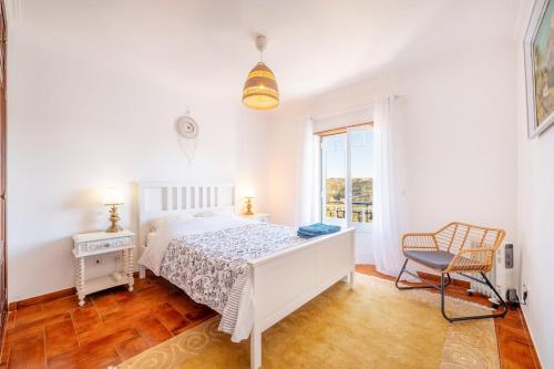 a white bedroom with a bed and a chair at Lovely vacation home in a picturesque countryside in Carvoeira