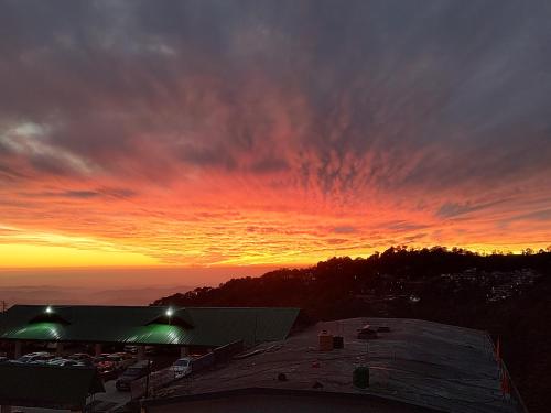 un tramonto su un edificio con un cielo di Om Yoga Ashram - 7 Days Yoga Meditation Retreat a Dharamshala