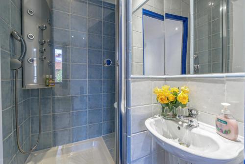 La salle de bains est pourvue de carrelage bleu, d'un lavabo et d'un miroir. dans l'établissement stay-cannes- 1 Bedroom beach & congress apartment, à Cannes