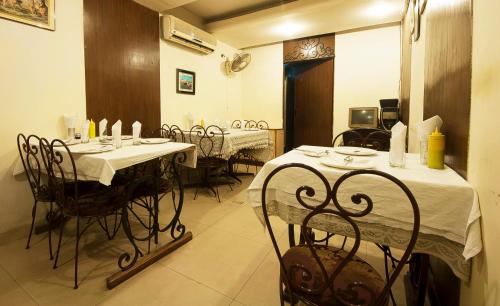 a dining room with tables and chairs with white table cloth at Golden Leaf Hotel in New Delhi