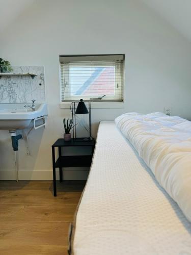 Un dormitorio con una cama grande y un lavabo en Zomerhuis - Gratis parkeren!, en Noordwijk aan Zee