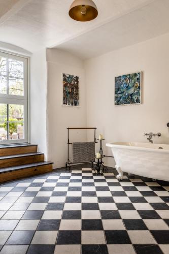 a bathroom with a black and white checkered floor and a tub at Gut Neuwerk in Kall