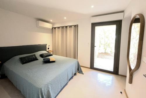 une chambre avec un lit et une grande fenêtre dans l'établissement Villa Cazélie, piscine vue splendide sur le Golfe, à Porto-Vecchio