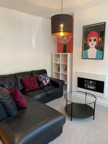 a living room with a black leather couch and a table at 3 Bed Family House Free Parking in Southend-on-Sea