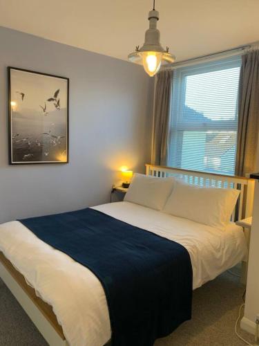 a bedroom with a bed with a blue blanket and a window at 3 Bed Family House Free Parking in Southend-on-Sea