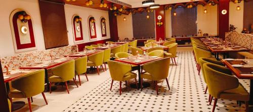 een eetkamer met tafels en gele stoelen bij Chinmay Hotel & Resort in Lucknow