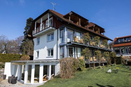 a large white house with a balcony at Hotel Haus am See in Nonnenhorn