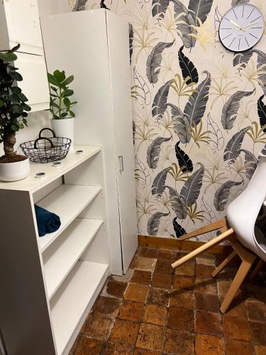 Cette chambre dispose de tiroirs blancs et d'un mur orné de papier peint à fleurs. dans l'établissement Studio départ tardif proche gare et lycées, à Orléans