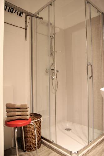 a glass shower with a red stool in a bathroom at Cosy gezellig app met aparte gastenkamer op 30meter van strand privé garage in Koksijde