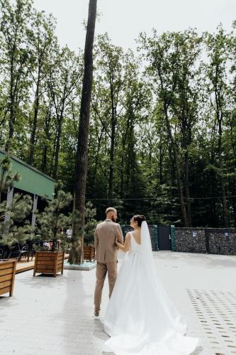 a bride and groom walking through a park at Rado Hotel Spa in Khmil'nyk