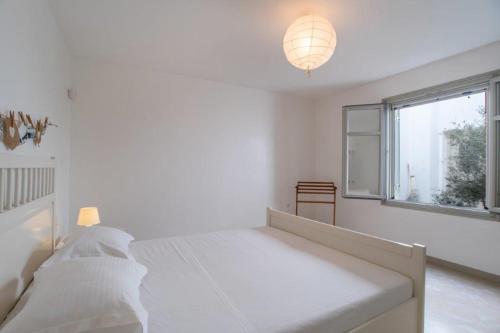 a white bedroom with a bed and a window at Piperi On The Rocks in Naousa