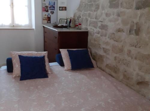 a room with two blue pillows and a stone wall at Apartments Agava & Lucija in Povlja