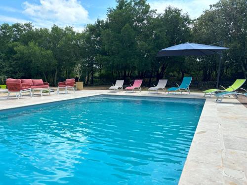 - un groupe de chaises et un parasol à côté de la piscine dans l'établissement Villa 6 pers avec Parc - Piscine - Pool house - Calme -, à Méjannes-le-Clap