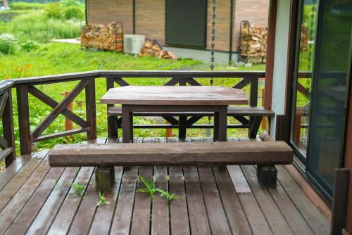 a wooden bench sitting on a porch with a swing at 八ヶ岳 HOKUTO BASE -Yatsugatake- in Hokuto