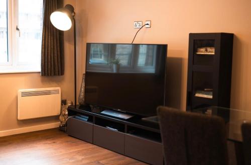 a living room with a flat screen tv on a entertainment center at Modern apartment in the city centre in Southampton