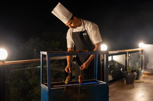 a chef preparing food in a box at night at StayVista at Barkat Villa with Jacuzzi in Rāmgarh
