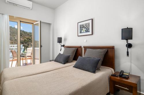 a bedroom with two beds and a balcony at Glaros Hotel Apartment in Agia Galini
