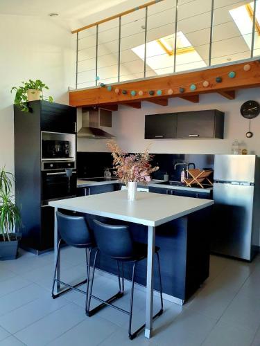 une cuisine avec une table blanche et des chaises bleues dans l'établissement L'Or du temps, appartement cosy, à Roanne
