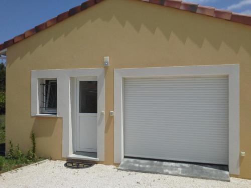 une porte de garage devant une maison dans l'établissement Appartement T2 tout équipé, à Le Fauga
