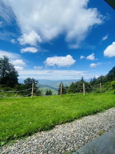 a grassy hill with a fence and a blue sky at Simba Jungle Lodge, Binsar Wildlife Sanctuary in Binsar