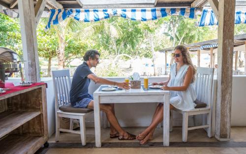 a man and a woman sitting at a table at Puri Sari Beach Hotel in Labuan Bajo
