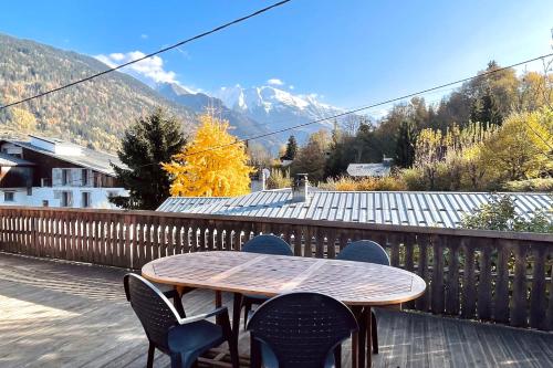 une table et des chaises en bois sur une terrasse avec des montagnes dans l'établissement Appartement du Rosay - Welkeys, à Saint-Gervais-les-Bains