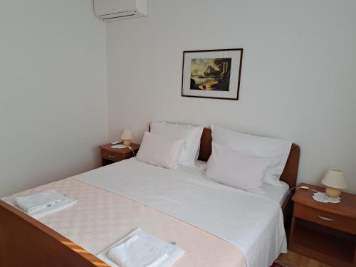 a bedroom with a bed with white sheets and pillows at Apartments Pink house in Povljana