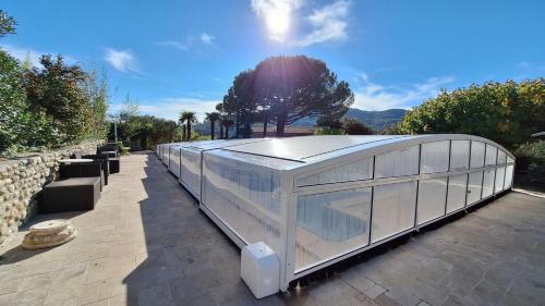 a glass house with a roof on a patio at Sous le Grand Pin Piscine & Spa Gîtes Éden en Cévennes à Anduze Gard in Anduze