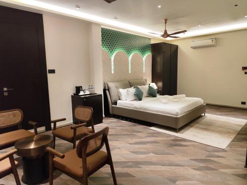 a bedroom with a bed and chairs in a room at The Long D Hotel and Banquet Surat Airport Rd in Surat