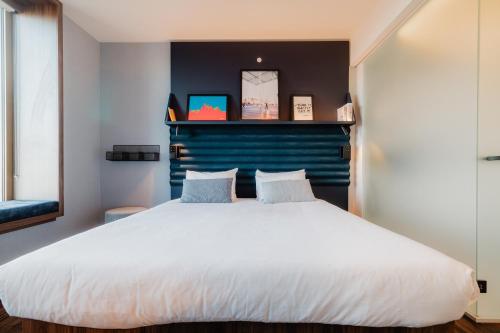 a bedroom with a large white bed with a blue headboard at A-STAY Antwerp in Antwerp