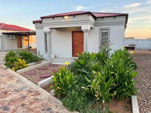 a small white house with a door and some plants at Mafikeng Boutique Lodge in Mahikeng