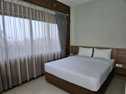a bed in a room with a large window at Amerta Giri Hotel Dieng Wonosobo in Kejajar