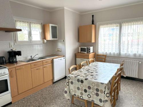 une cuisine avec une table recouverte d'une nappe dans l'établissement Maison à 500m de la mer et à 100m des commerces à TREGASTEL - Réf 20, à Trégastel