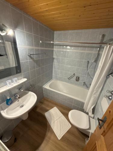 a bathroom with a sink and a toilet and a tub at Gasthof Und Hotel Maria Gern in Berchtesgaden